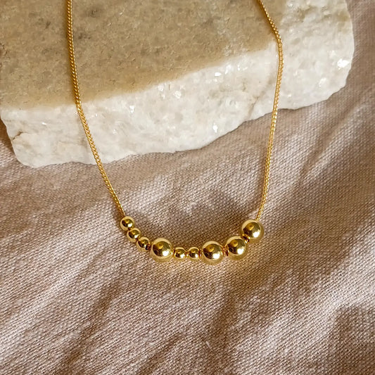 Kultainen Viesti-kaulakoru, jossa lukee morseaakkosilla kirjoitettuna Ilo.