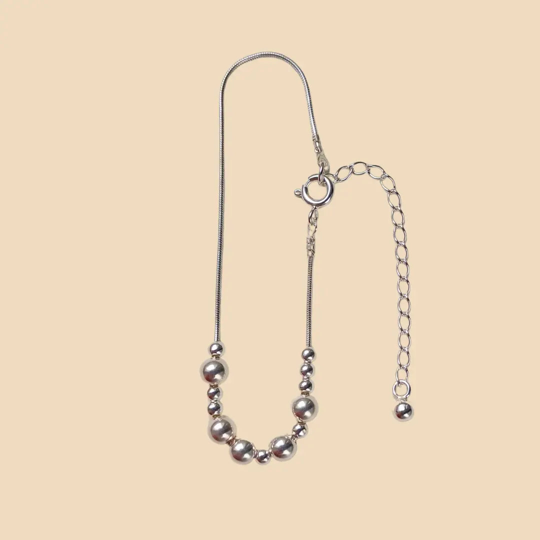 Hopeinen rannekoru, jossa lukee morseaakkosilla rakas.