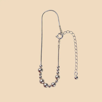 Hopeinen rannekoru, jossa lukee morseaakkosilla rakas.