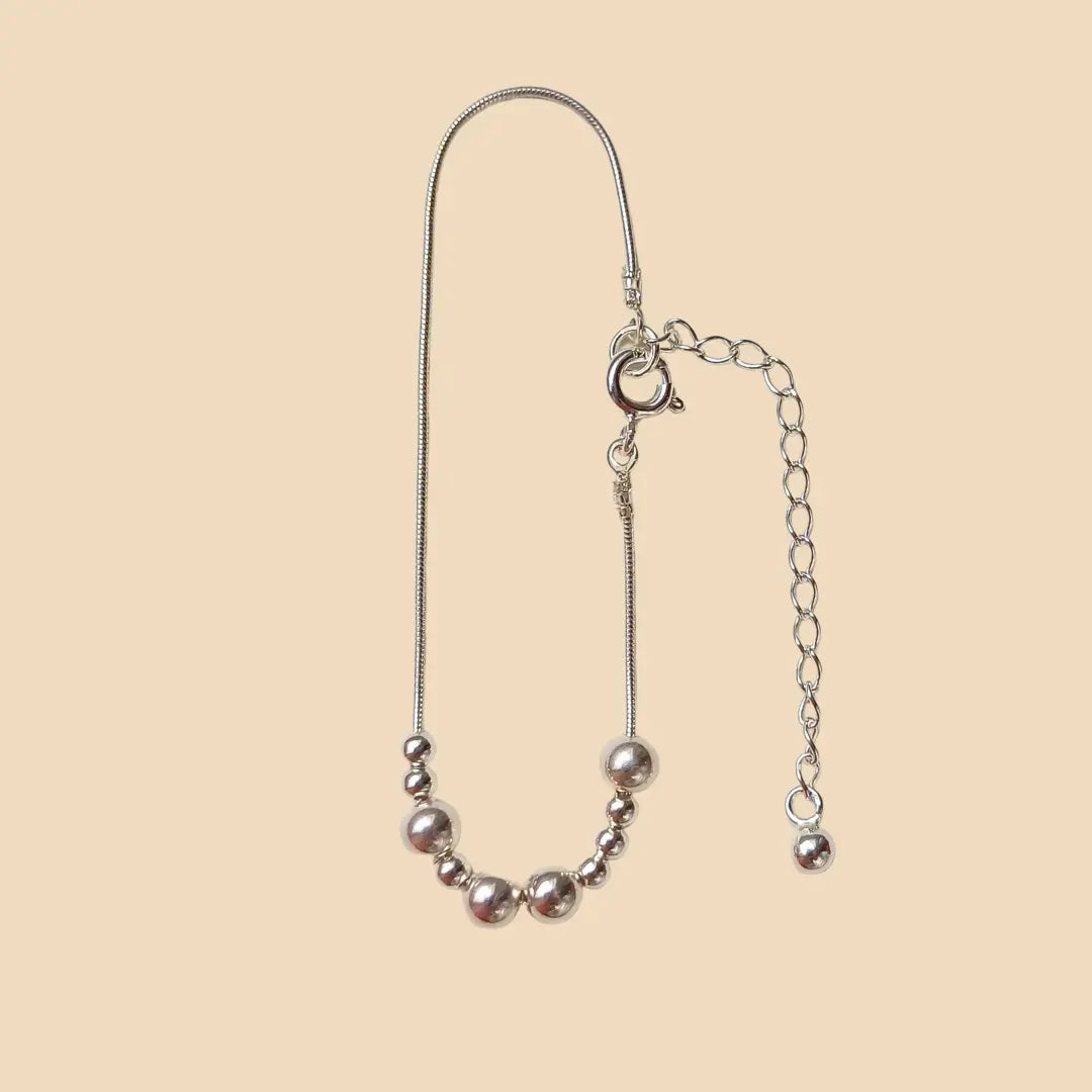 Hopeinen rannekoru, jossa lukee morseaakkosilla upea.