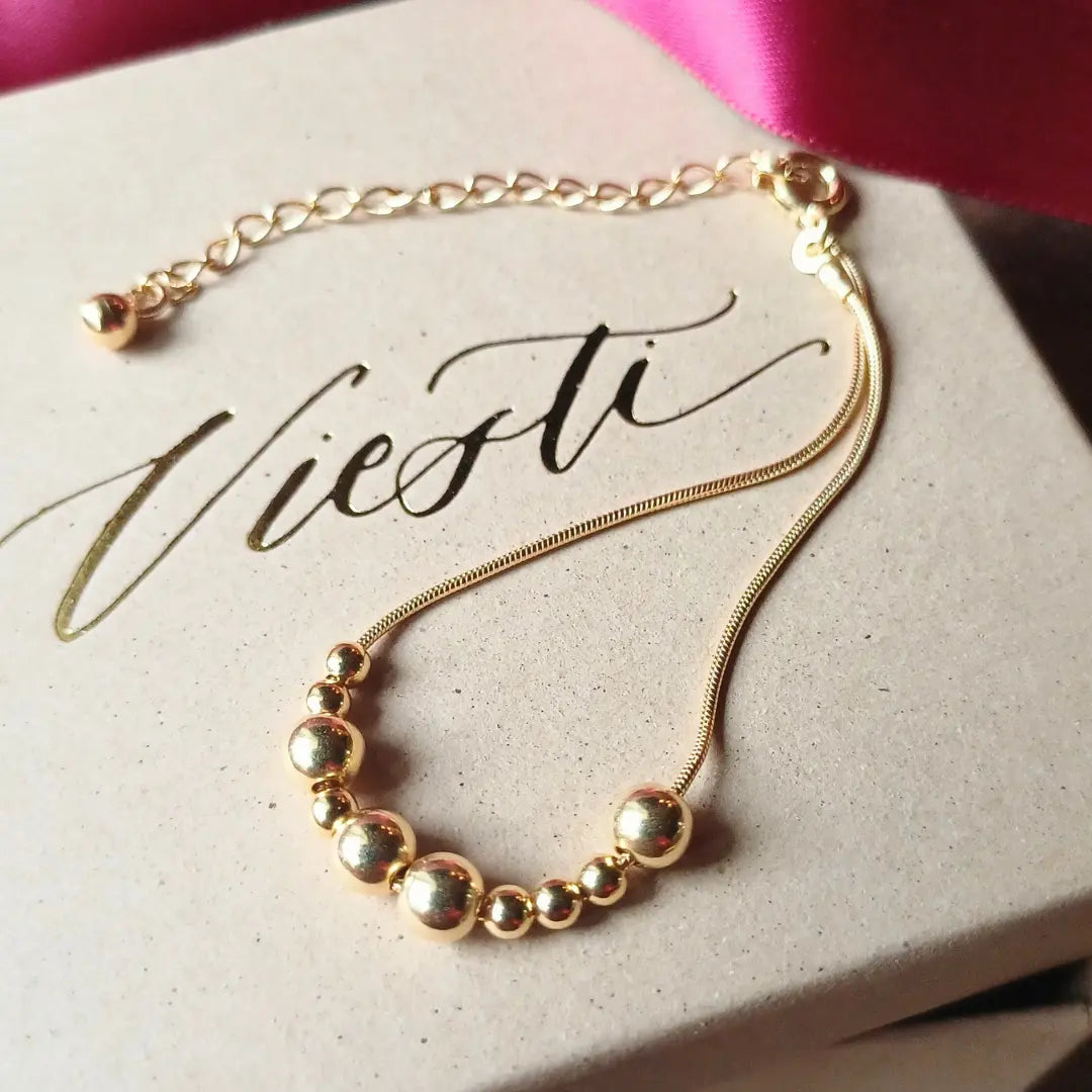 Kultainen Viesti-rannekoru, jossa lukee morseaakkosilla Upea.