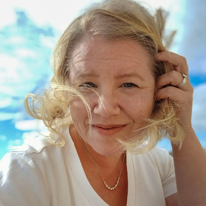 Vaalealla naisella on kaulassaan hopeinen Viesti-koru, jossa lukee morseaakkosilla Vapaus.