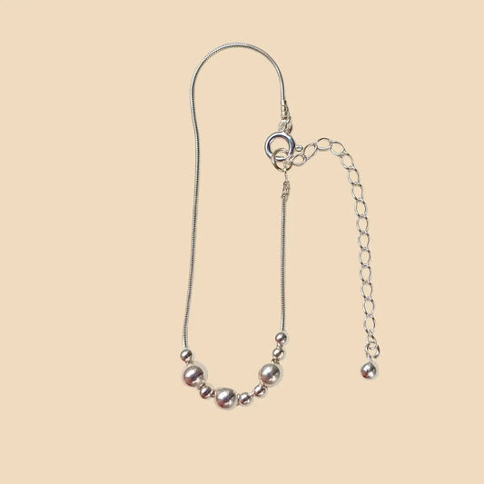 Hopeinen rannekoru. jossa lukee morseaakkosilla äiti