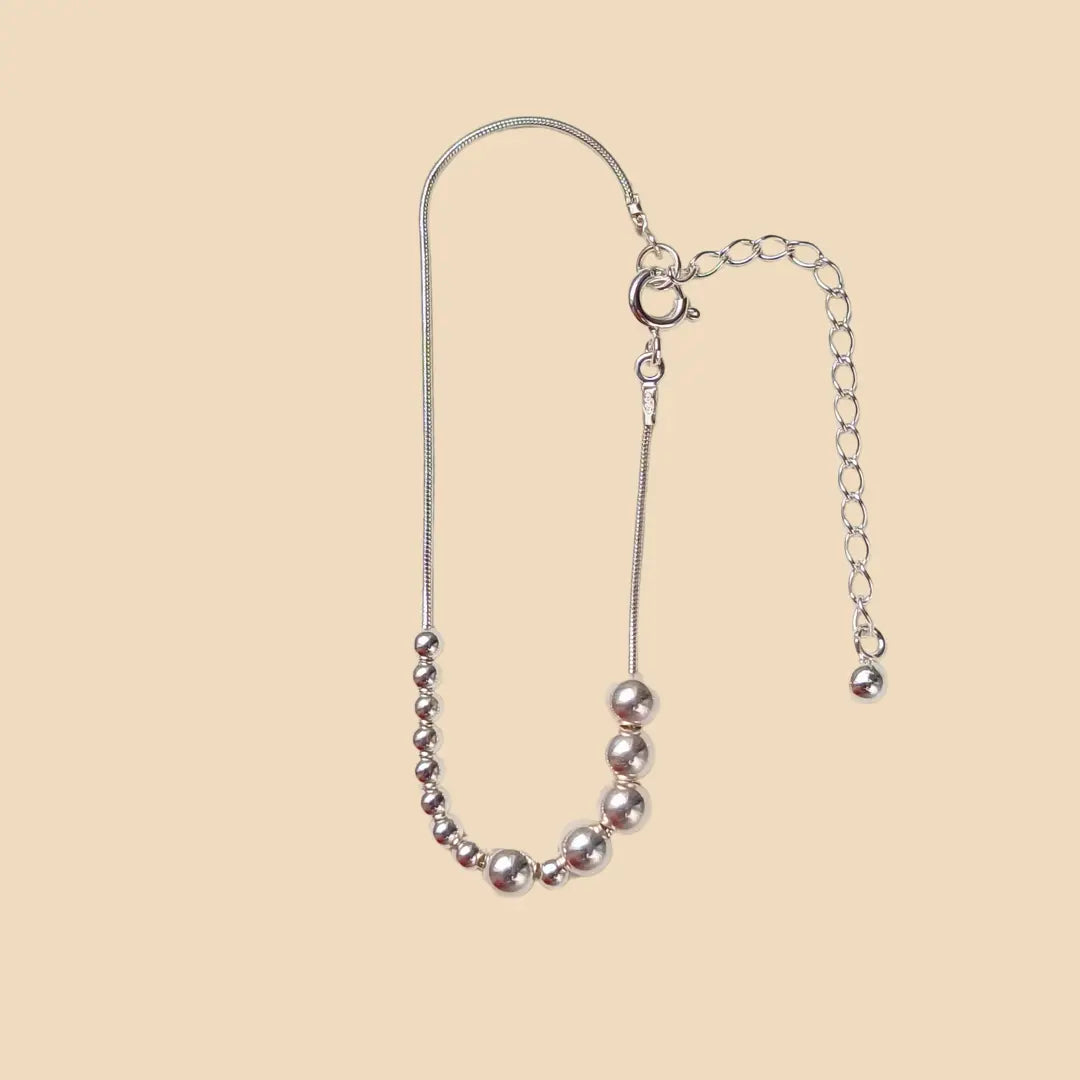 Hopeinen rannekoru, jossa lukee sisko morseaakkosilla