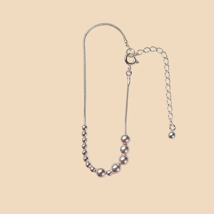 Hopeinen rannekoru, jossa lukee sisko morseaakkosilla